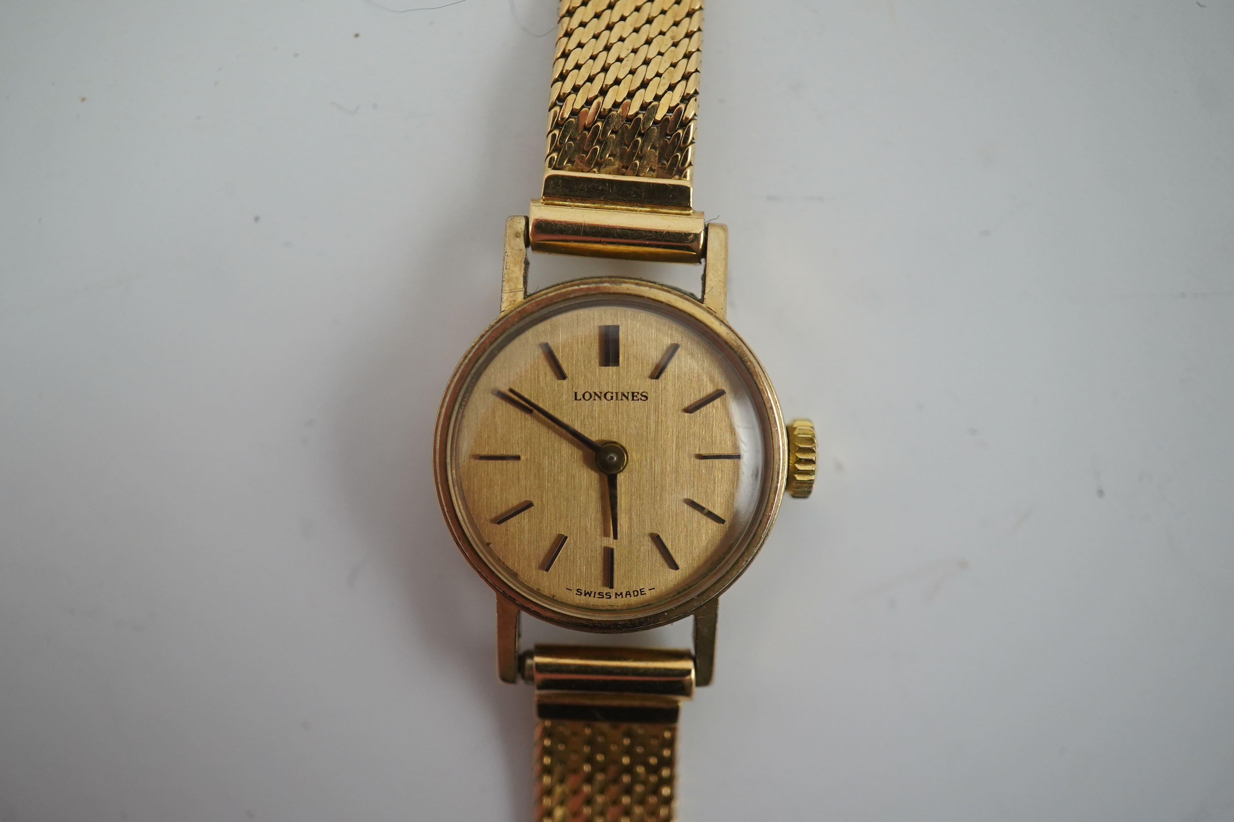 A lady's modern 9ct gold Longines manual wind wrist watch, on an Italian 18k gold bracelet